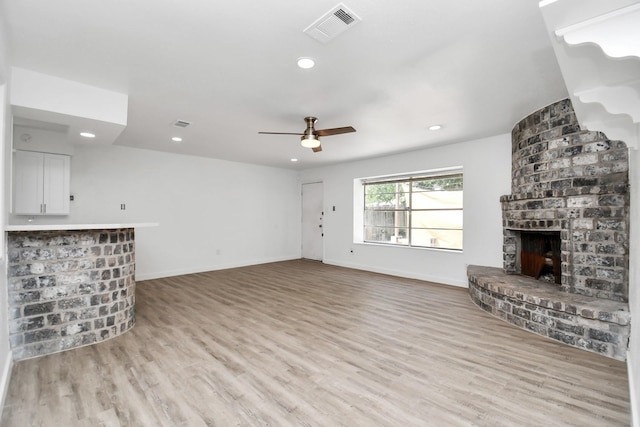 unfurnished living room featuring ceiling fan, a fireplace, and light hardwood / wood-style flooring