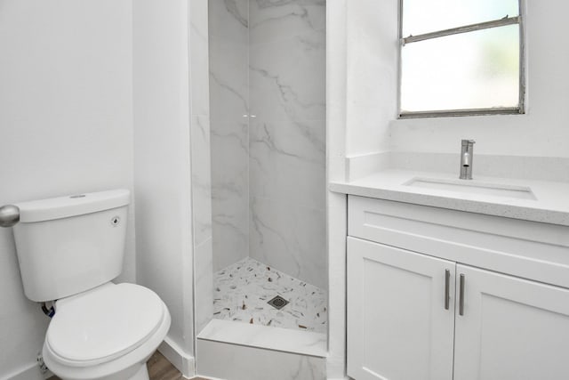 bathroom featuring vanity, toilet, and tiled shower