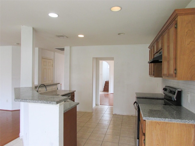 kitchen with kitchen peninsula, decorative backsplash, light stone counters, and black range with electric cooktop