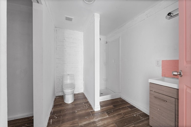 bathroom featuring hardwood / wood-style flooring, walk in shower, vanity, and toilet