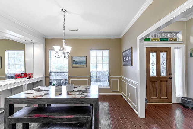 dining space featuring crown molding, plenty of natural light, dark wood-type flooring, and an inviting chandelier