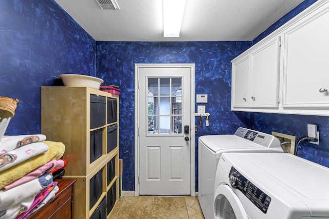 laundry area featuring cabinets, washer and dryer, and a textured ceiling