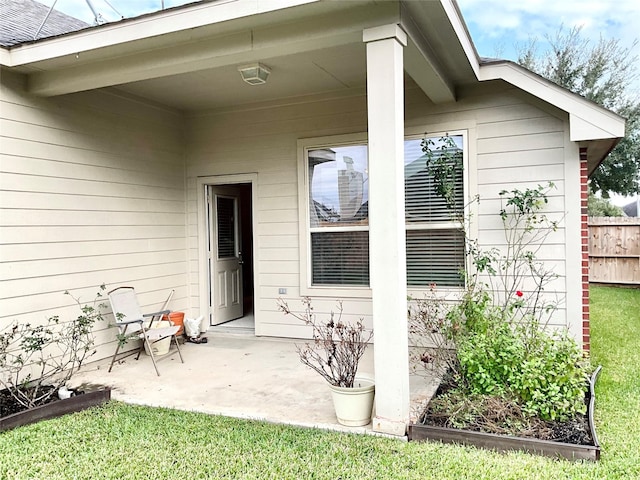 view of exterior entry with a patio and a lawn