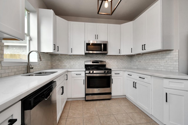 kitchen with stainless steel appliances, light tile patterned flooring, sink, and white cabinets