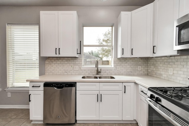 kitchen featuring white cabinetry, sink, decorative backsplash, light tile patterned floors, and stainless steel appliances