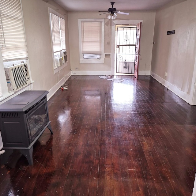 unfurnished living room featuring cooling unit, dark hardwood / wood-style floors, ceiling fan, and a wood stove