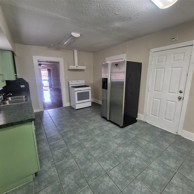 kitchen with sink, dark tile patterned floors, stainless steel fridge with ice dispenser, white gas stove, and a textured ceiling