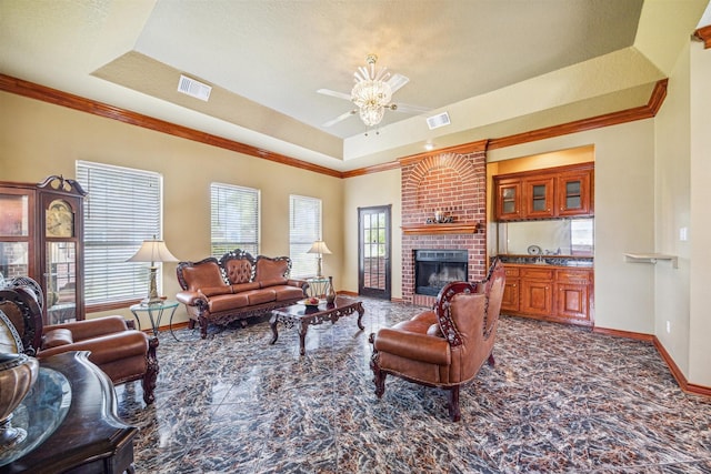 living room featuring a fireplace, ornamental molding, a raised ceiling, and ceiling fan