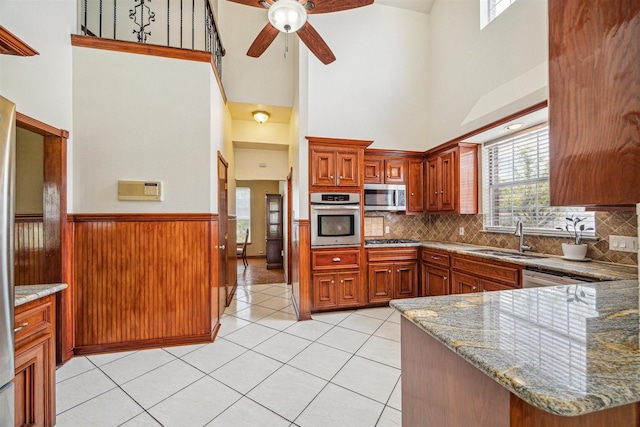 kitchen with sink, stainless steel appliances, kitchen peninsula, and stone countertops