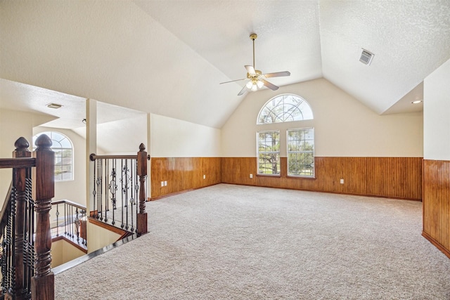 spare room with vaulted ceiling, a textured ceiling, and wood walls