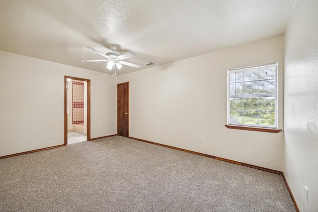 empty room featuring ceiling fan, light colored carpet, and a textured ceiling