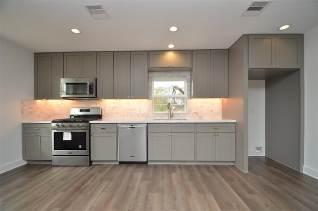 kitchen featuring stainless steel appliances, sink, light hardwood / wood-style flooring, and gray cabinets