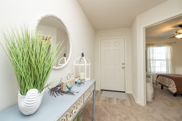 foyer featuring light carpet and ceiling fan