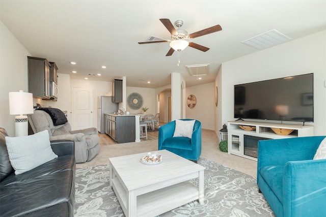 living room with sink, light carpet, and ceiling fan