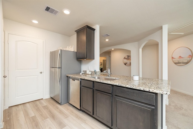 kitchen with sink, light hardwood / wood-style flooring, stainless steel appliances, dark brown cabinetry, and light stone countertops