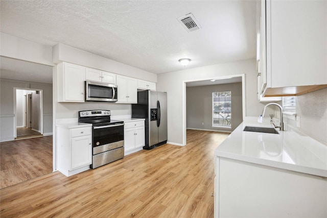 kitchen featuring light wood-type flooring, appliances with stainless steel finishes, sink, and white cabinets