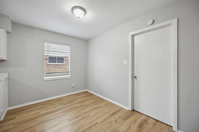 empty room with light hardwood / wood-style flooring and a textured ceiling