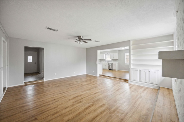 unfurnished living room featuring ceiling fan, a textured ceiling, and light hardwood / wood-style floors