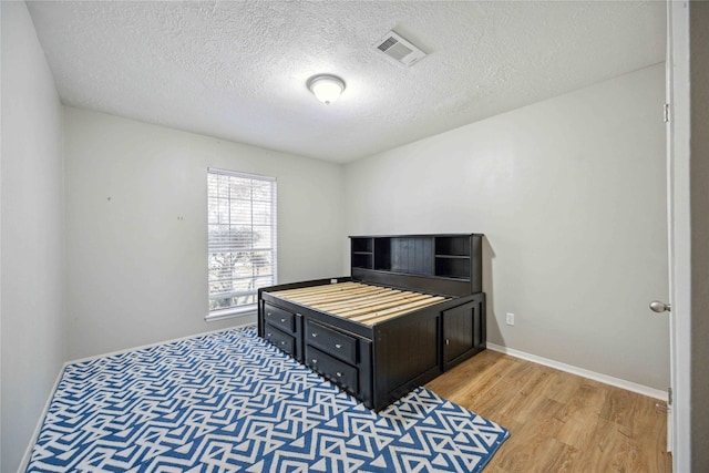 bedroom featuring hardwood / wood-style flooring and a textured ceiling