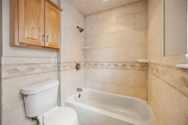 bathroom featuring toilet, tiled shower / bath combo, and tile walls