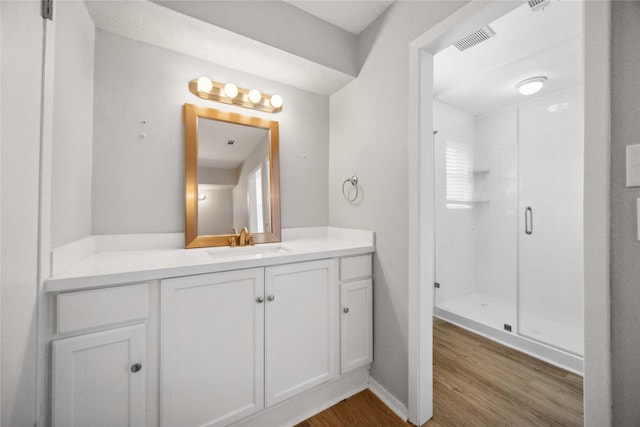 bathroom with vanity, a shower with shower door, and hardwood / wood-style floors