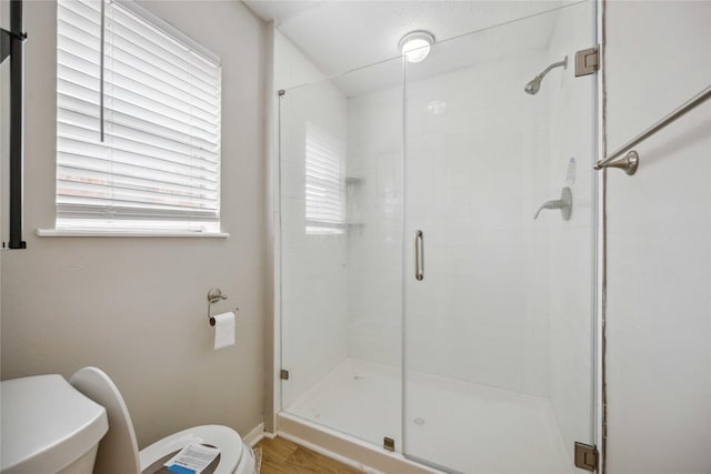 bathroom featuring toilet and a shower with shower door