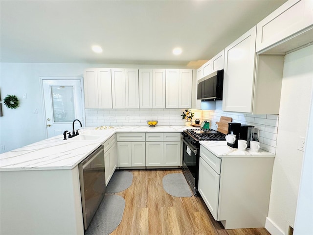 kitchen with sink, white cabinetry, stainless steel dishwasher, black gas stove, and light hardwood / wood-style floors