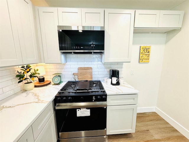 kitchen featuring range with gas cooktop, white cabinetry, light stone countertops, light hardwood / wood-style floors, and decorative backsplash