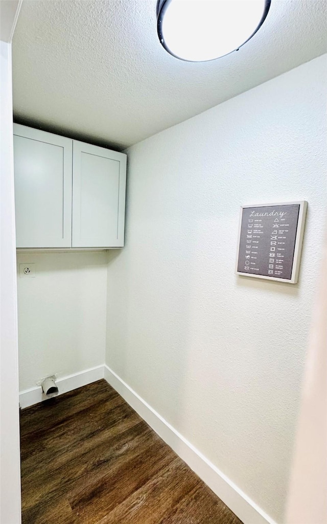 washroom featuring dark wood-type flooring, cabinets, and a textured ceiling