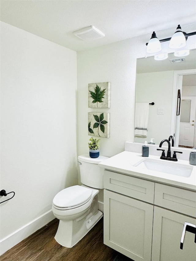 bathroom featuring toilet, visible vents, wood finished floors, and vanity