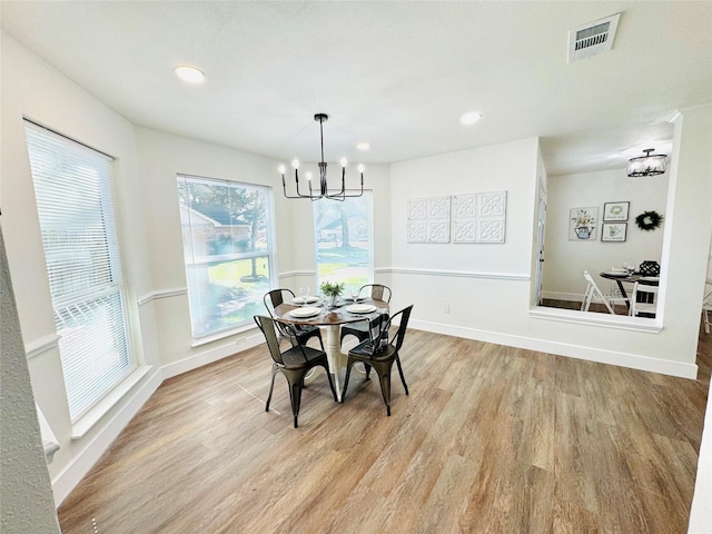 dining space with light wood-style floors, visible vents, baseboards, and an inviting chandelier