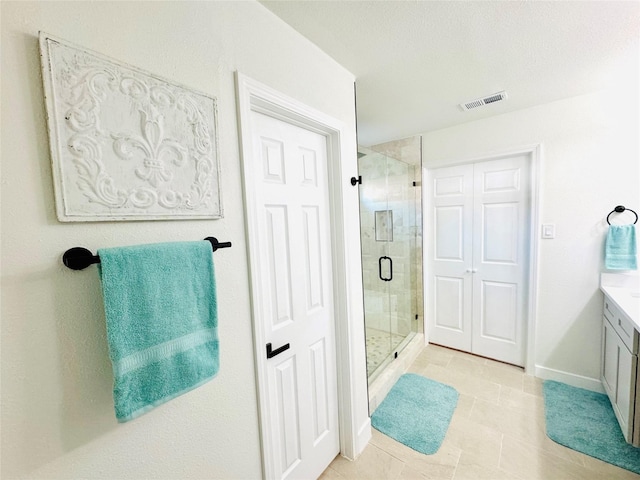 bathroom with a shower with door, vanity, and tile patterned flooring