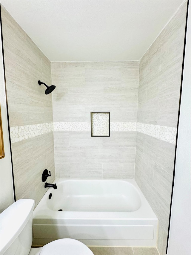 bathroom featuring toilet and tiled shower / bath combo