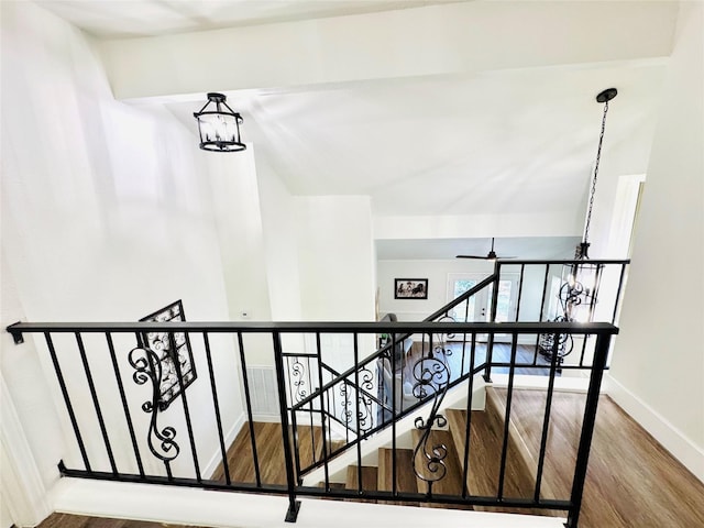 staircase featuring ceiling fan with notable chandelier, wood finished floors, and baseboards