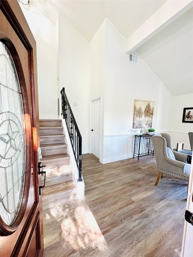 entrance foyer featuring beam ceiling, high vaulted ceiling, and light wood-type flooring