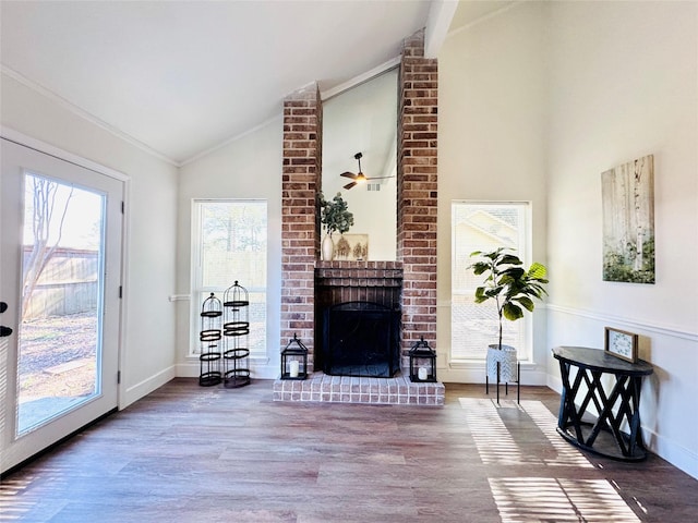 living area with a fireplace, baseboards, vaulted ceiling, and wood finished floors