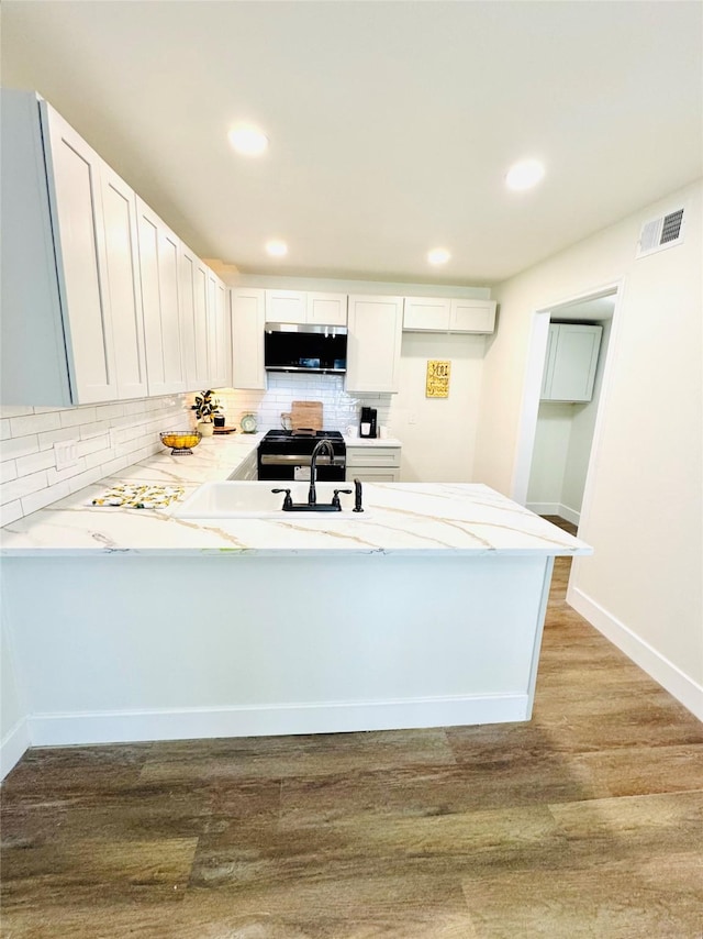 kitchen featuring white cabinetry, kitchen peninsula, sink, and light wood-type flooring