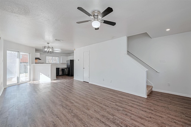 unfurnished living room with ceiling fan with notable chandelier, hardwood / wood-style floors, and a textured ceiling