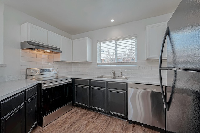 kitchen with sink, white cabinetry, appliances with stainless steel finishes, light hardwood / wood-style floors, and decorative backsplash