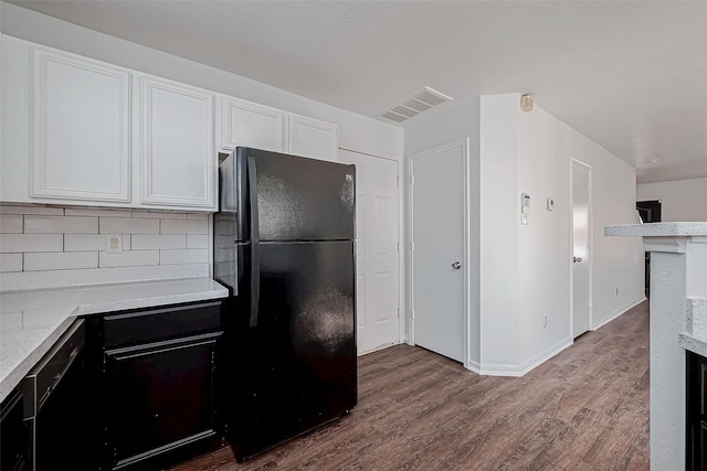 kitchen with white cabinets, decorative backsplash, hardwood / wood-style flooring, light stone counters, and black appliances