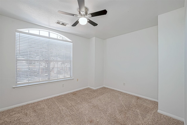 spare room featuring ceiling fan, a textured ceiling, light carpet, and a wealth of natural light