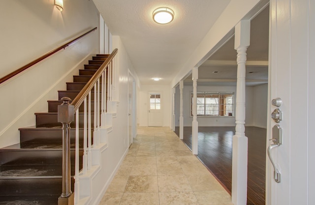 tiled foyer entrance with ornate columns and a textured ceiling