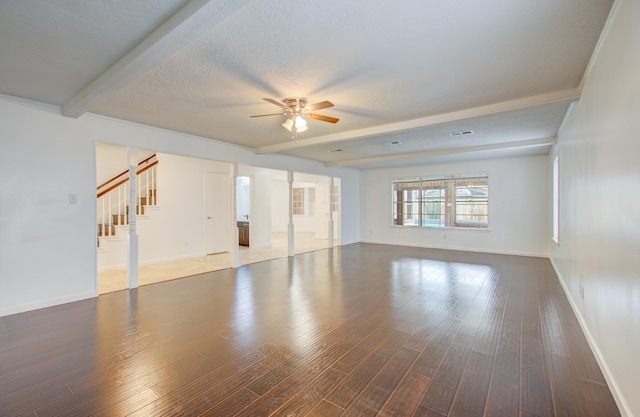 spare room featuring ceiling fan, dark wood-type flooring, beamed ceiling, and a textured ceiling