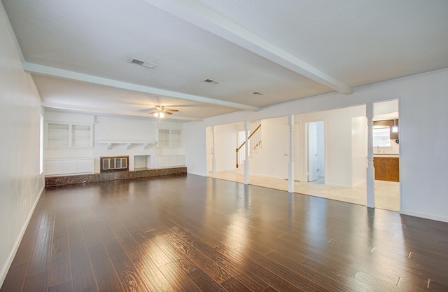 unfurnished living room featuring beamed ceiling, ceiling fan, wood-type flooring, and a fireplace