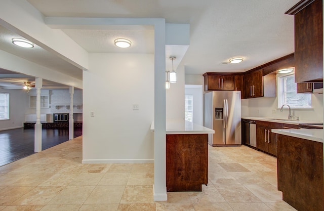 kitchen with sink, a textured ceiling, pendant lighting, ceiling fan, and stainless steel appliances