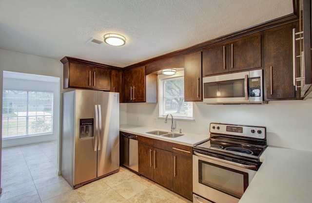 kitchen with dark brown cabinetry, sink, a textured ceiling, and appliances with stainless steel finishes