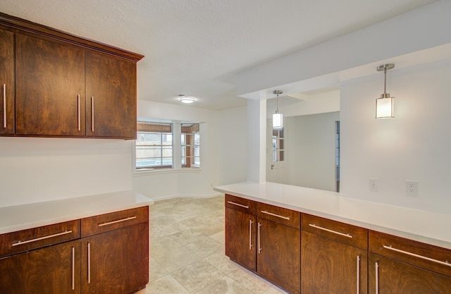 kitchen featuring dark brown cabinets, pendant lighting, and a textured ceiling