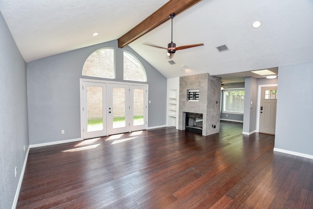 unfurnished living room with dark wood-type flooring, lofted ceiling with beams, built in features, ceiling fan, and a tiled fireplace