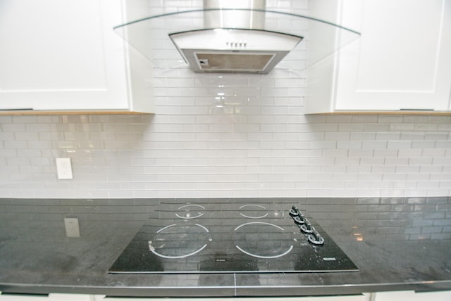 interior details featuring ventilation hood, white cabinetry, tasteful backsplash, dark stone countertops, and black electric stovetop