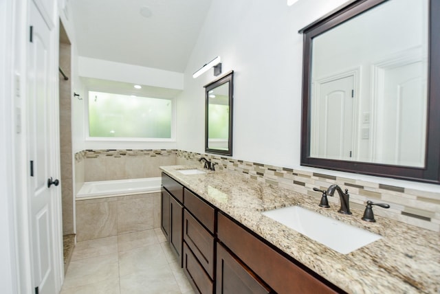 bathroom with tasteful backsplash, lofted ceiling, tile patterned flooring, vanity, and tiled tub